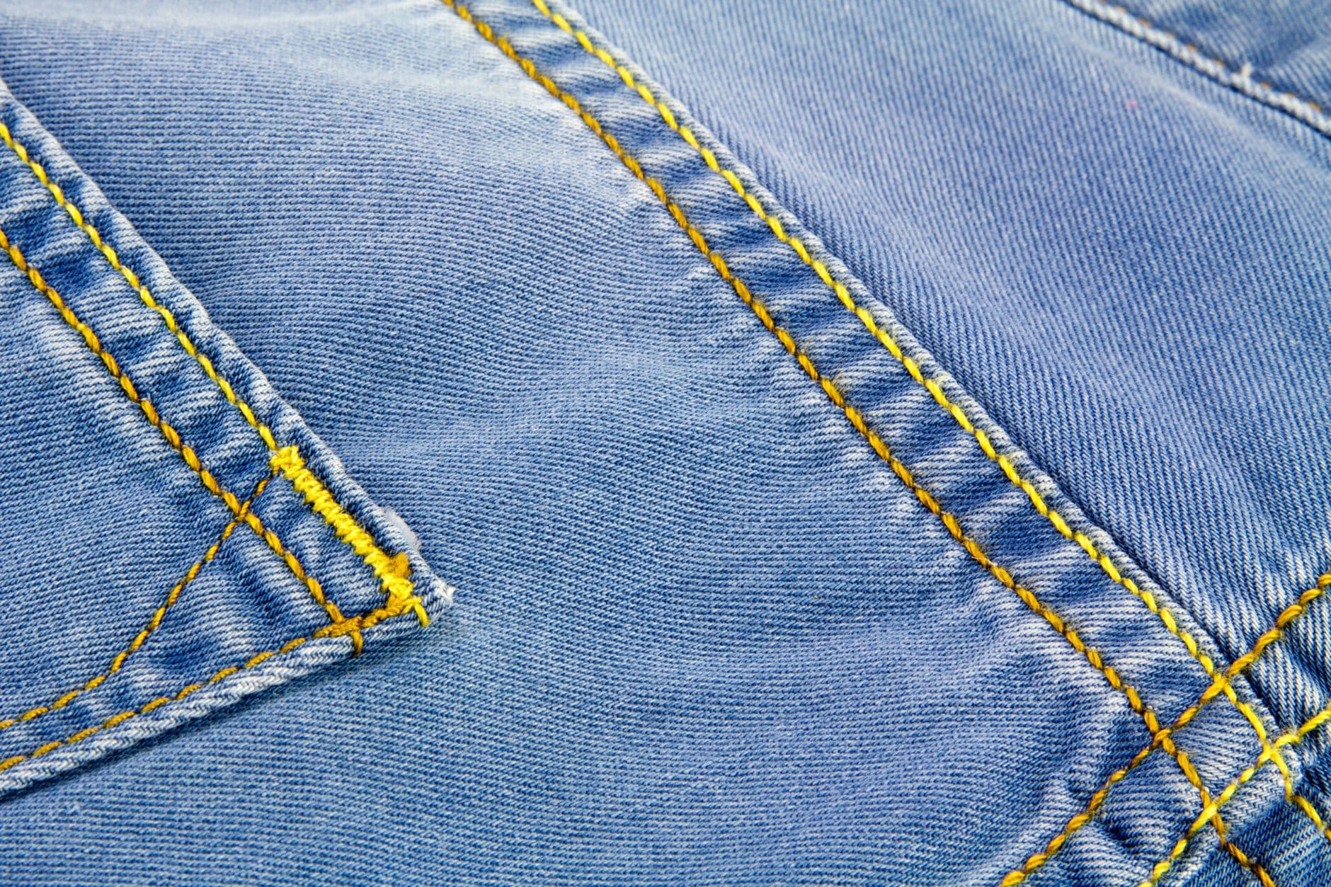 Poly-Cotton Twill — Detailed close-up of blue denim fabric showcasing yellow stitching and texture.