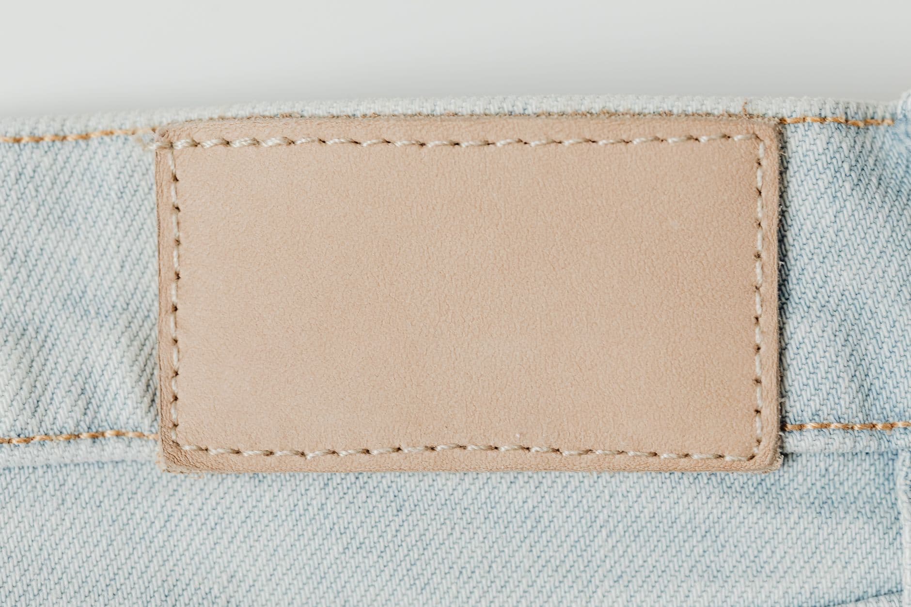 Macro shot of light denim jeans with a blank leather patch for branding.